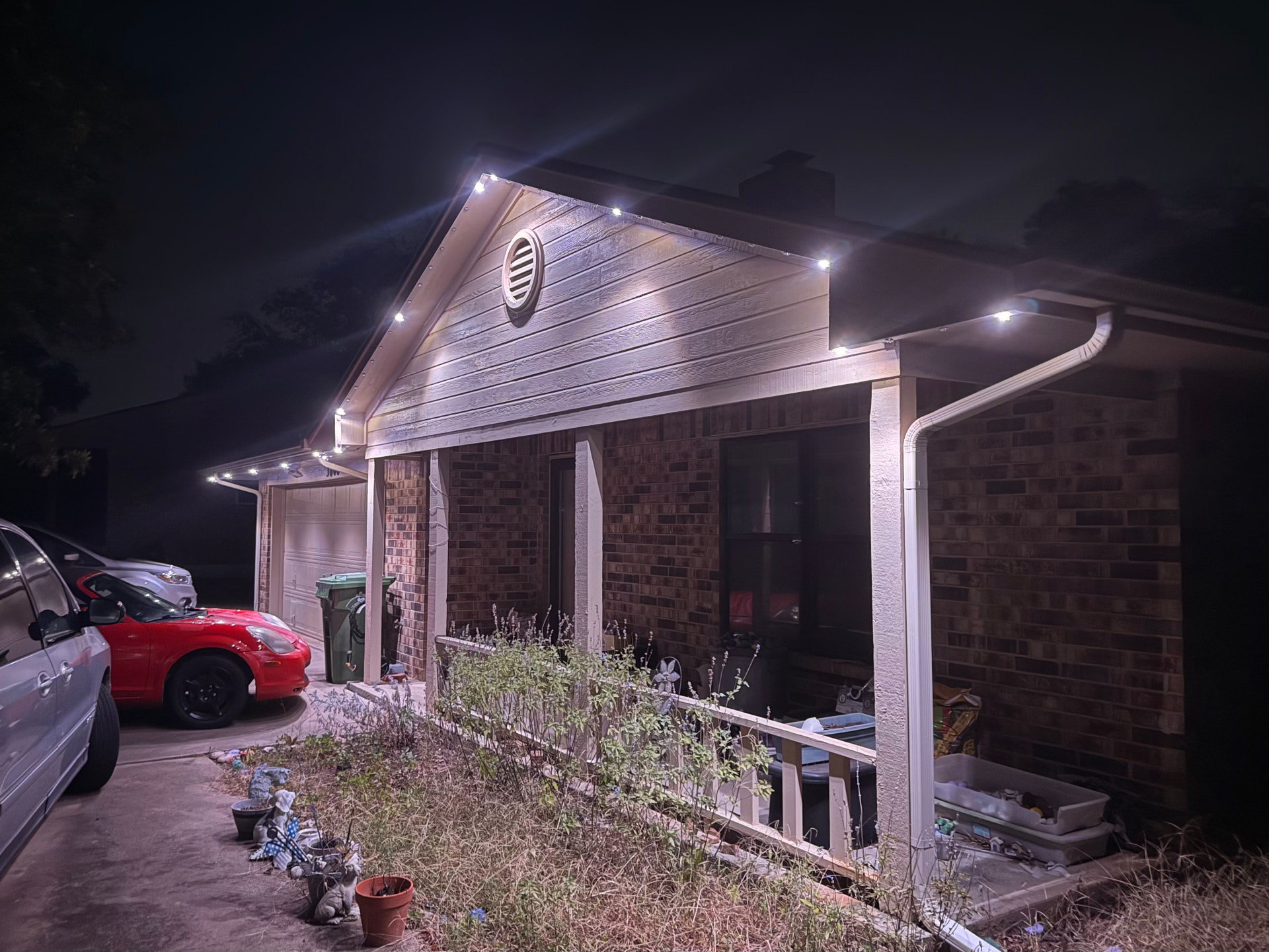 Covered porch illuminated by cool-white permanent lights behind the fascia along the gable and eaves